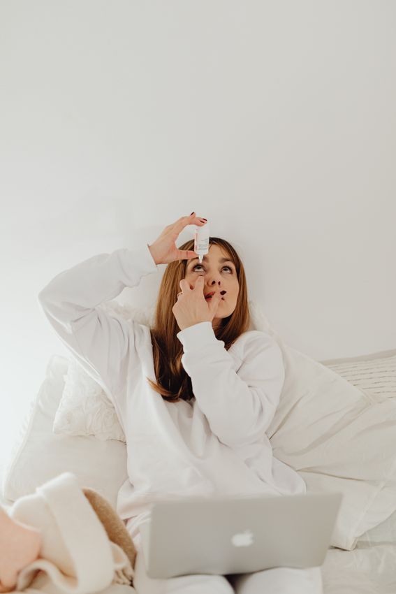 A person instilling artificial tear drops into a dry, irritated eye