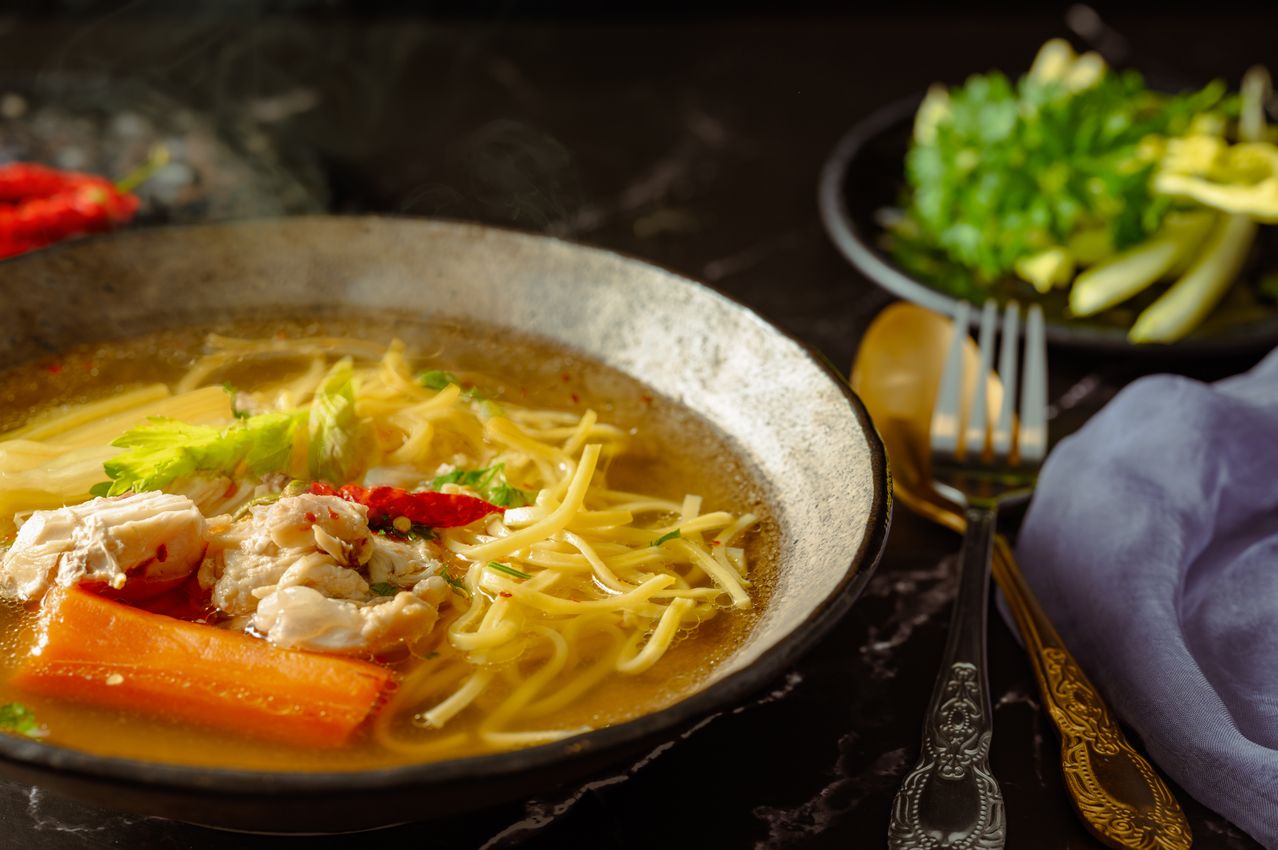 A bowl of light chicken soup with herbal tea and fresh fruit