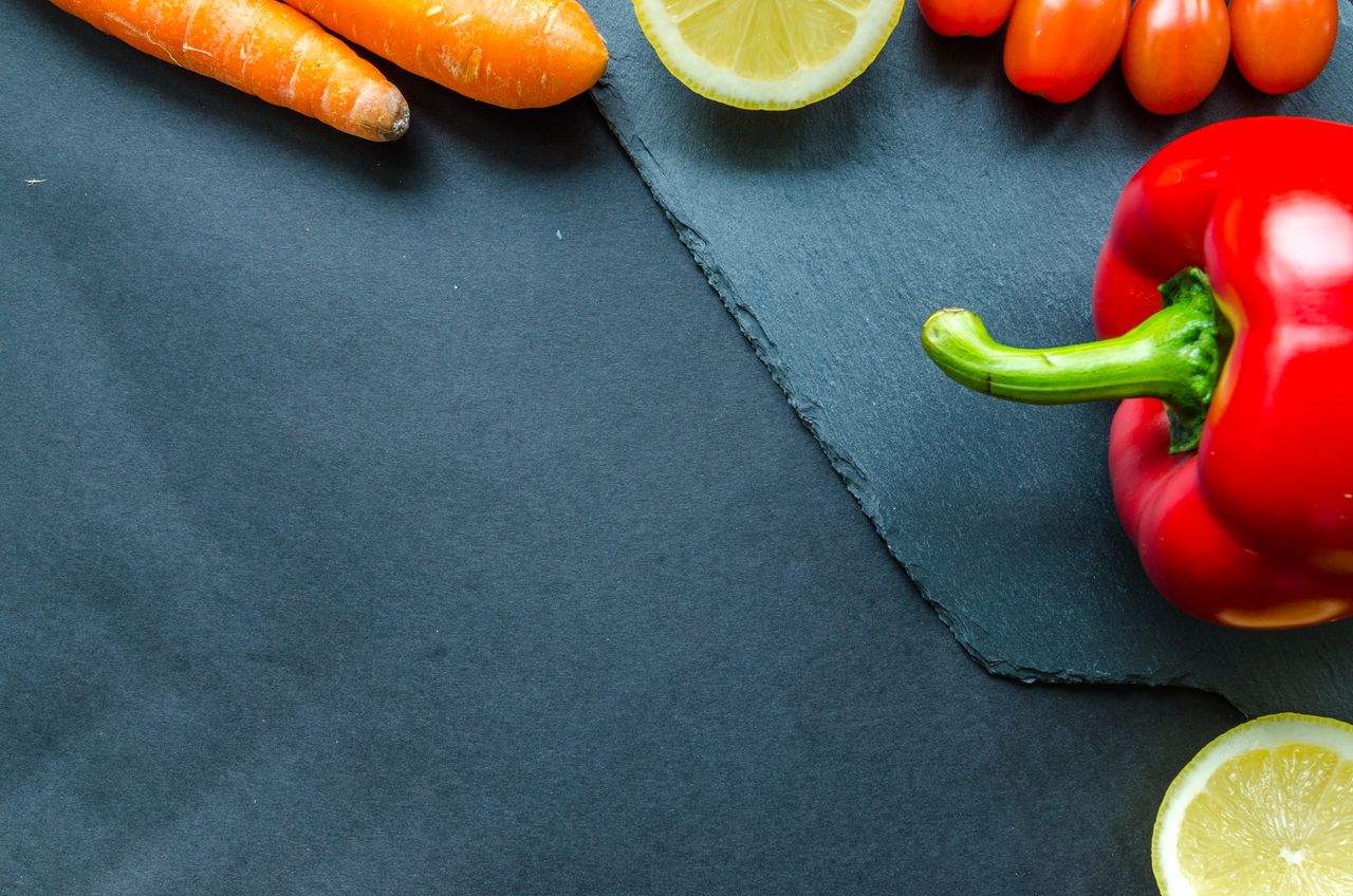 A colorful table spread of carrots, leafy greens, fish, eggs, citrus and nuts