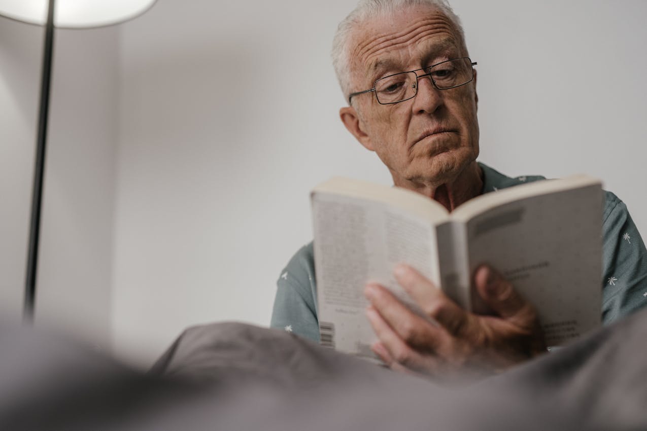 An older adult holding a book at arm's length to read more clearly